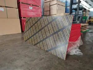 Lembar Triplek Phenolic Film Face merek Kuda Hitam yang siap dijual, berdiri tegak di gudang Indoho. Plywood bekisting anti air terbaik untuk proyek konstruksi dan cor beton. Stok melimpah.
