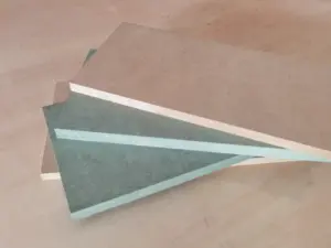 Perbandingan antara MDF Hijau Lestari (Moisture Resistant) dan MDF Standar, menunjukkan inti hijau sebagai penanda ketahanan terhadap kelembapan. Cocok untuk area dapur dan kamar mandi. Distributor Indoho.