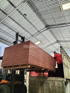 Proses pemuatan tumpukan triplek kontainer 28mm full kruing ke truk pengiriman di gudang distributor container flooring plywood Indonesia.
