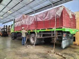 Staf memastikan keamanan muatan triplek cor phenolic sebelum dikirim ke lokasi proyek konstruksi