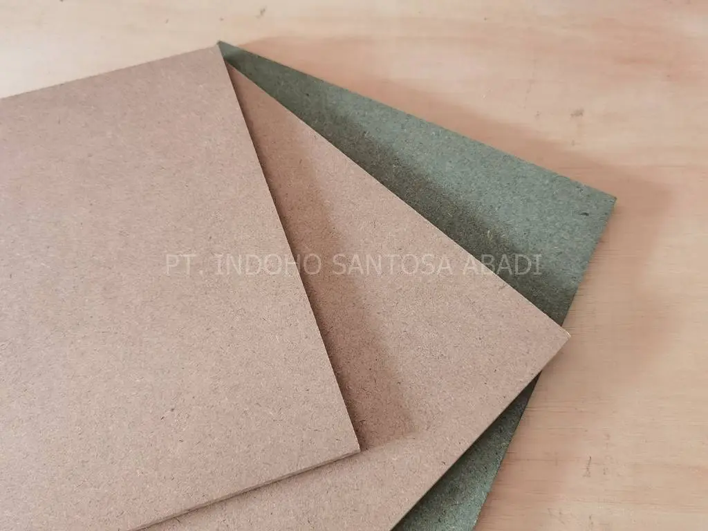 Tumpukan papan MDF standar berwarna cokelat bersanding dengan MDF HMR tahan lembap berwarna hijau dari distributor PT Indoho Santosa Abadi.