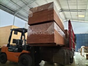 Forklift sedang memuat stok triplek kontainer 28mm full kruing ke truk pengiriman di gudang distributor container flooring plywood Indonesia.